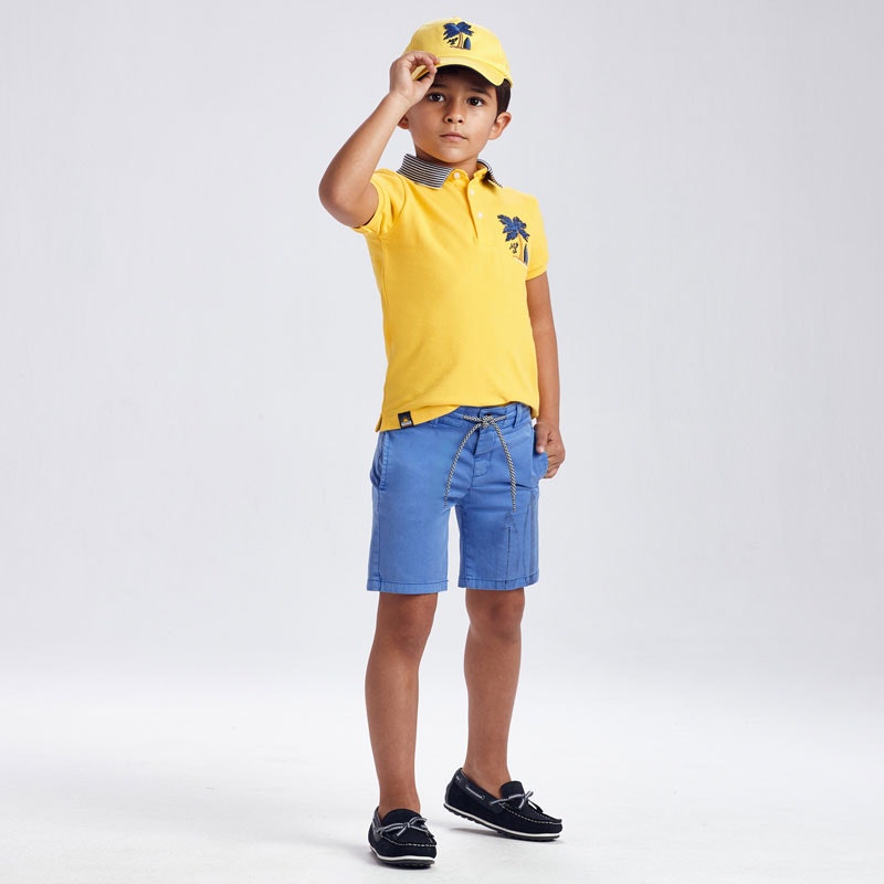 rapaz vestido com sapatos de vela, calções azuis e polo amarelo e chapéu amarelo da mayoral